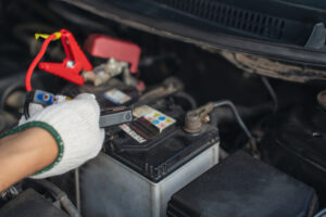 Eine Hand verbindet Starthilfekabel mit einer Autobatterie, um das Auto zu starten. Dieser Tipp aus dem Auto Batterie leer Ratgeber zeigt, wie man eine leere Batterie überbrückt.