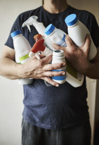 Eine Person hält verschiedene Reinigungs- und Pflegeprodukte wie Sprays und Flüssigkeiten. Der Auto Rostschutz Tipps Ratgeber empfiehlt die Verwendung geeigneter Produkte, um Rost vorzubeugen.