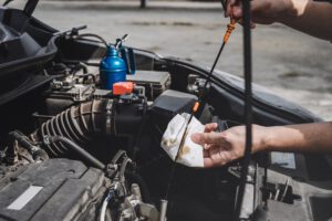 Eine Person überprüft den Ölstand im Motorraum eines Autos mit einem Peilstab. Ein wichtiger Tipp aus dem Ölverlust Auto erkennen Ratgeber, um einen möglichen Verlust zu erkennen.
